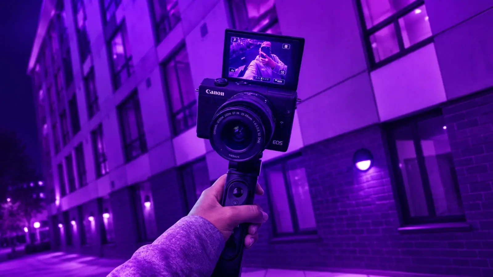 purple lit Canon camera held up by creator at night representing Indian creator camera confidence 2026